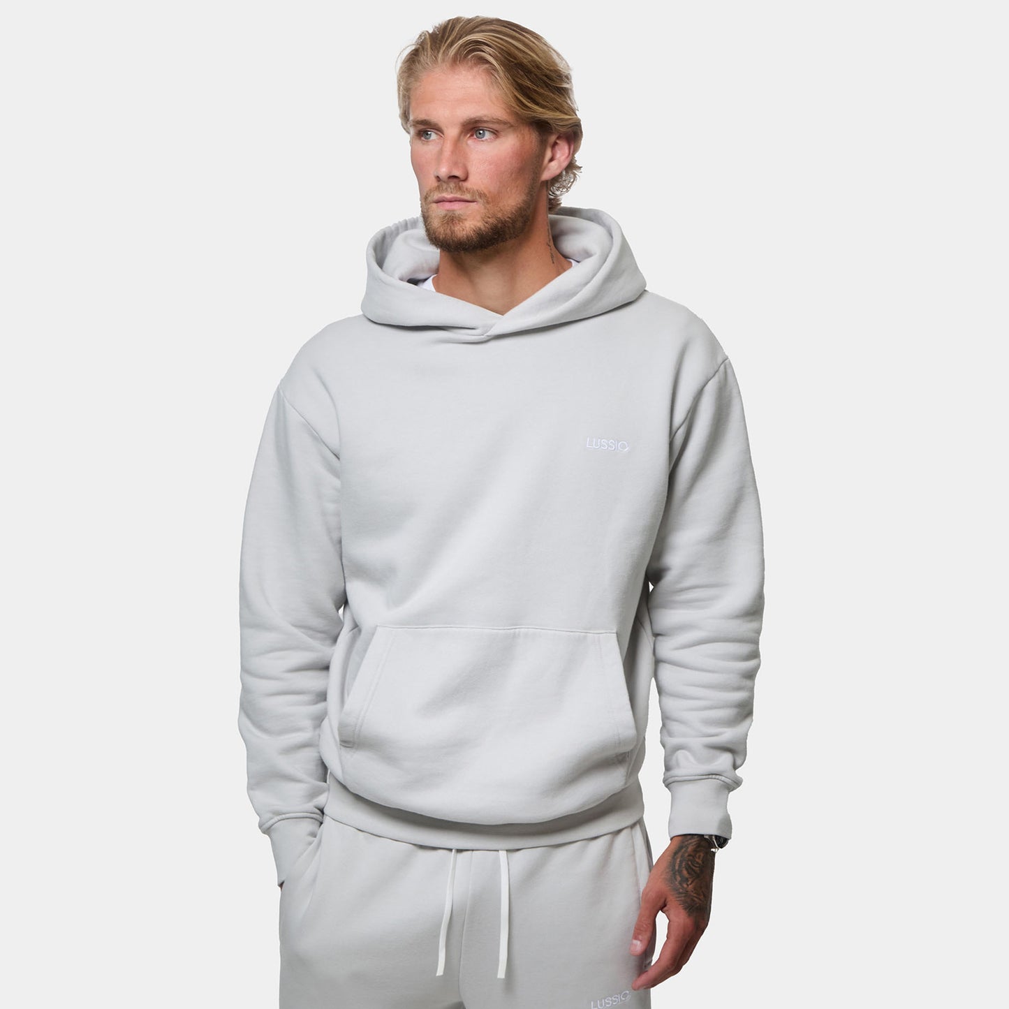 Half body shot of hoodie showing how it looks, model looking away from the camera with hand in pocket, front view