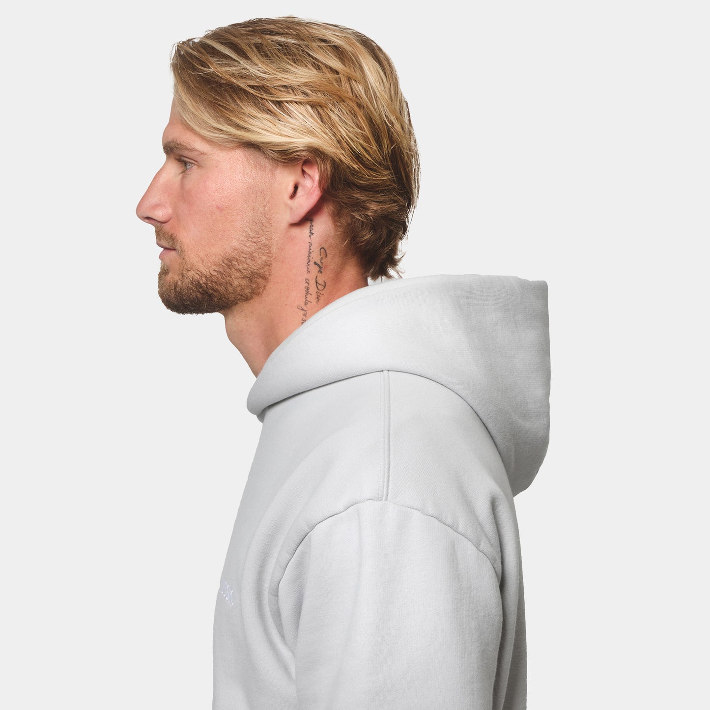 Model Posing side on to the camera wearing his Ice Grey Tracksuit, showing the hood shape and size, side view