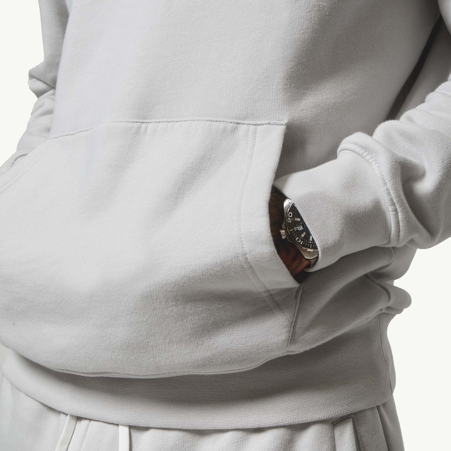 Close up shot of model with hands in his hoodie pocket wearing his Ice Grey Tracksuit, front view