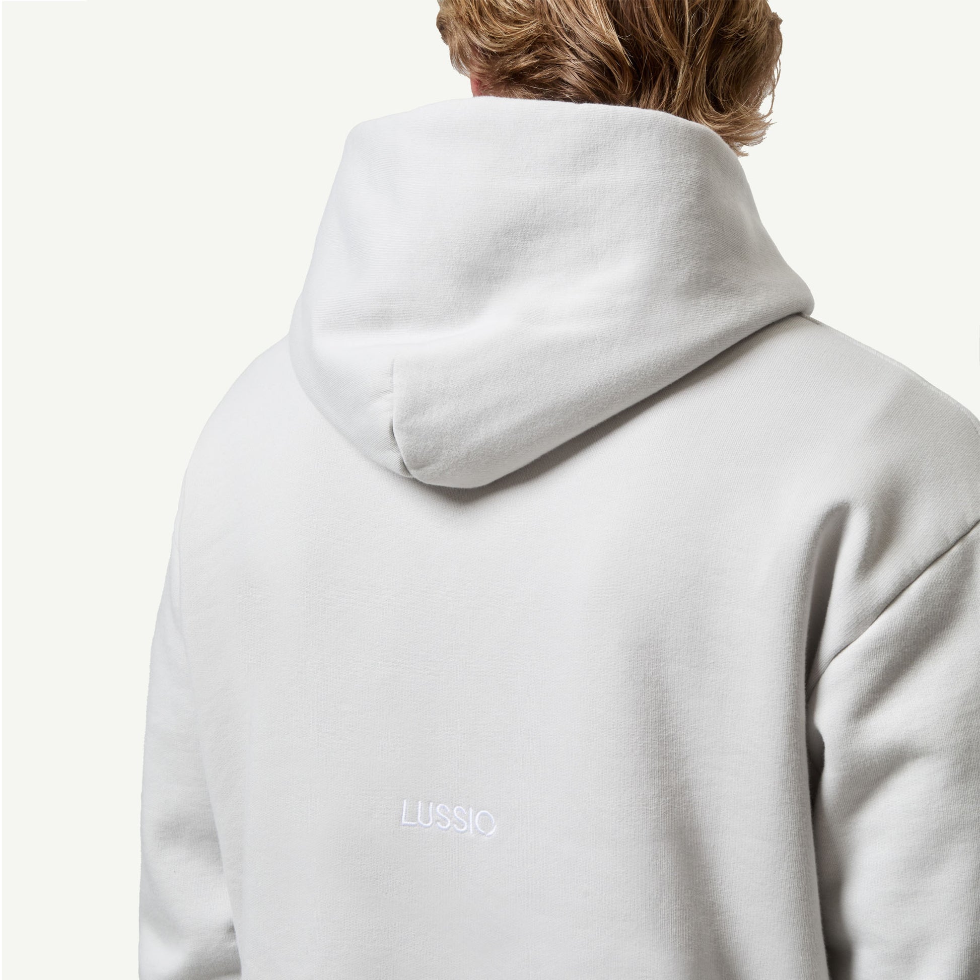 Close up shot of back Lussio logo and hood shape and size, model looking away from the camera, back view