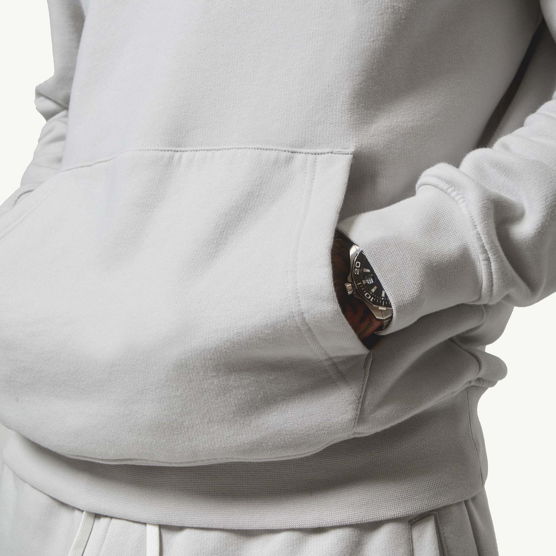 Close up shot of model with hands in his hoodie pocket wearing his Ice Grey Tracksuit, front view
