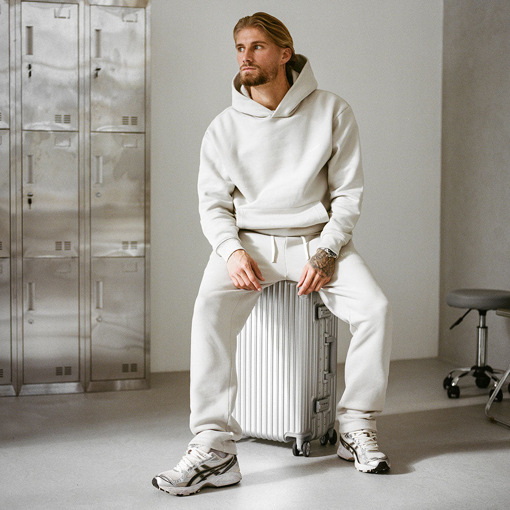 Model sat on a suitcase looking away from the camera, front view