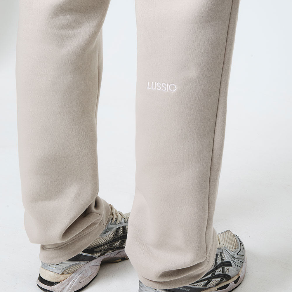 Stone sweatpants with 'LUSSIO' branding worn by the model on a white background