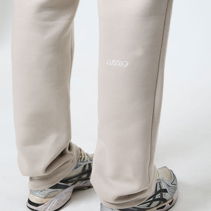 Stone sweatpants with 'LUSSIO' branding worn by the model on a white background