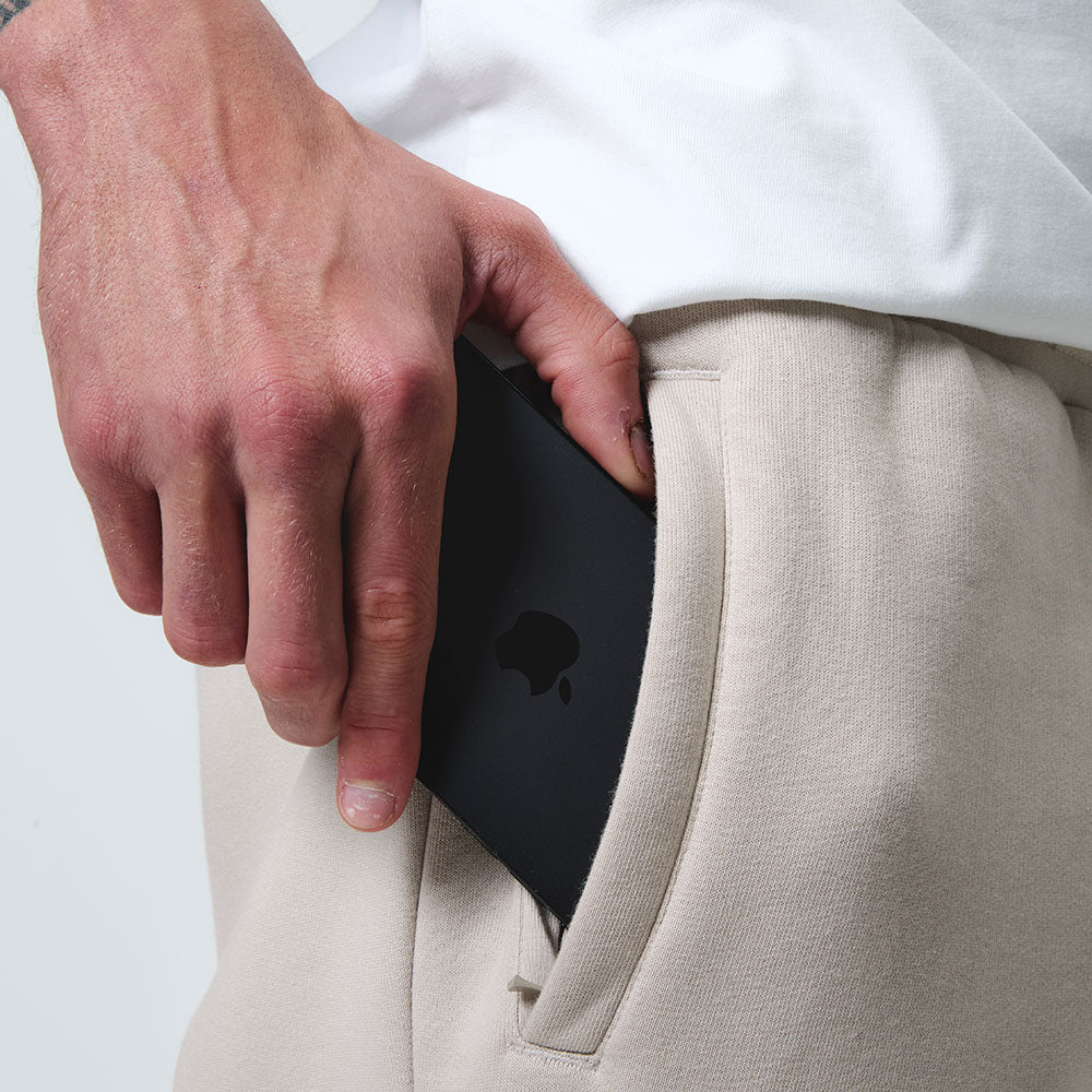 Close up on the Stone jogger detail, model putting his phone into zip pocket, front view